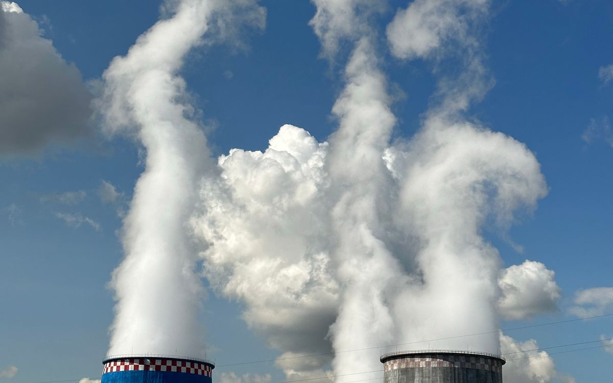 Industrial cooling towers releasing steam, representing thermal energy storage infrastructure for data center cooling systems